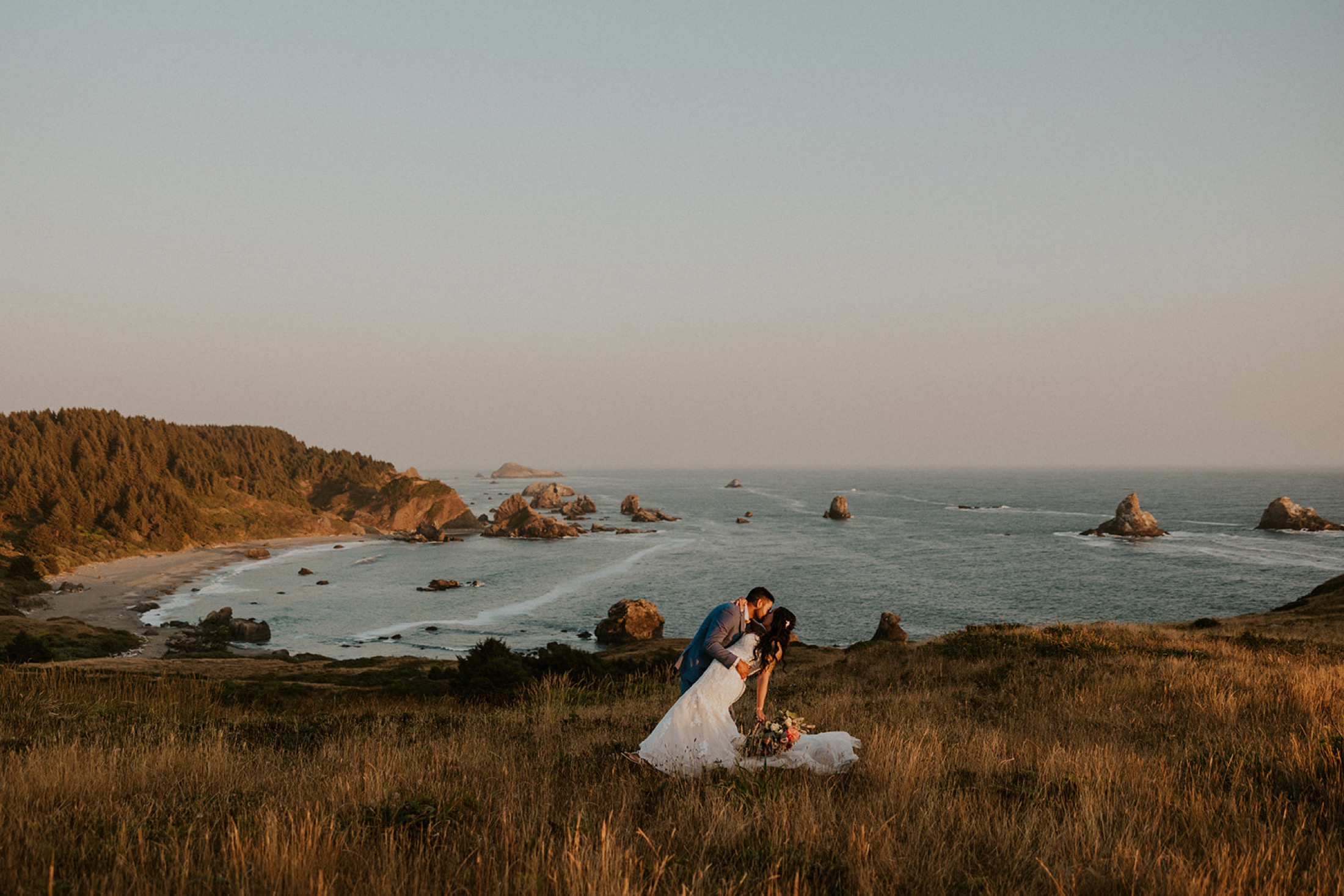 A couple at golden hour on an Oregon coast bluff above sea stacks