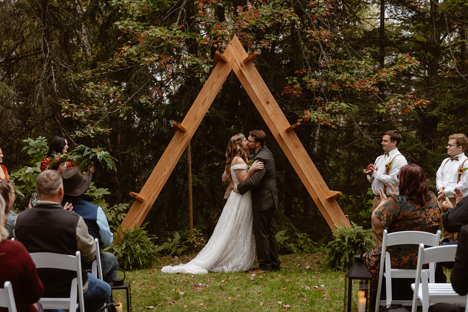 Couple's first kiss under a wooden A frame arch at a Voyageurs elopement ceremony