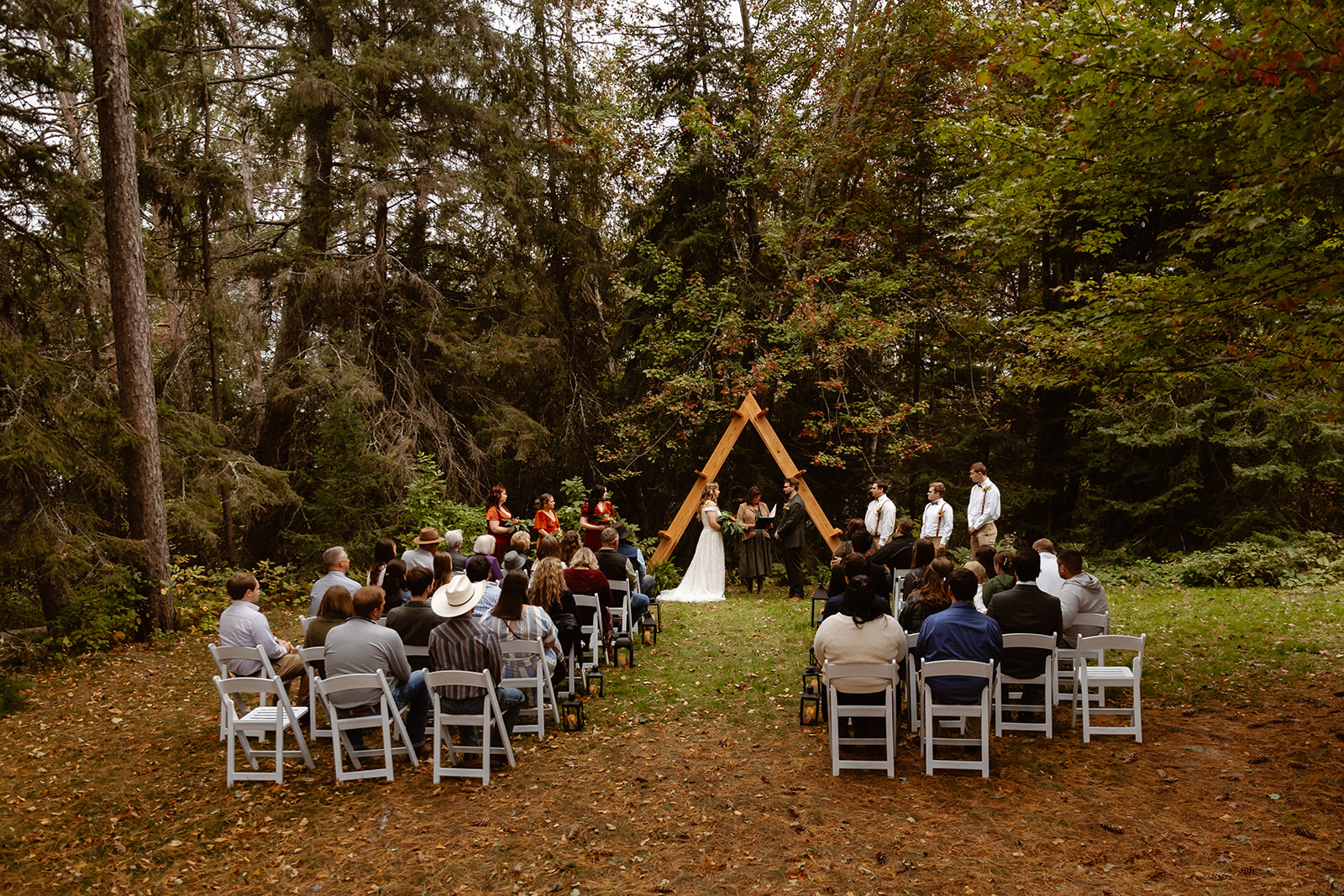 Intimate elopement ceremony under a wooden A frame arch in the forest at Voyageurs National Park